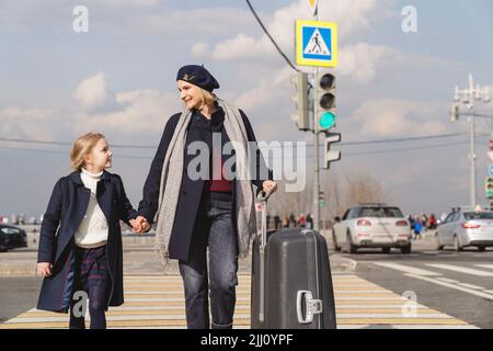Mamma e figlia stanno viaggiando in una grande città con una valigia. Foto Stock