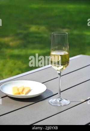 Un bicchiere di vino bianco secco si trova su un tavolo in giardino. Giorno d'estate Foto Stock