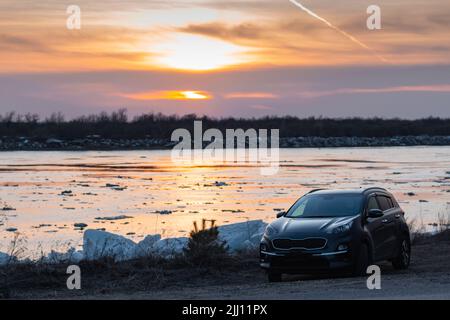 Fine deriva di ghiaccio sul fiume in primavera, 16 aprile 2022. Galleggiante di ghiaccio in primavera sullo sfondo del bellissimo cielo al tramonto. Auto si erge sul fiume Ban Foto Stock