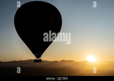 Una silhouette di una mongolfiera durante un volo all'alba a Sossusvlei, Namibia. Foto Stock