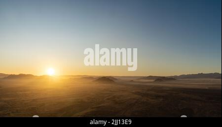 Alba vista da una mongolfiera durante un giro a Sossusvlei, Namibia. I raggi del sole si propagano sulle colline e sulle montagne del Namib-Desert. Foto Stock