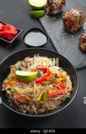 Spaghetti di vetro con verdure in una ciotola nera su sfondo grigio. Cucina Asiatica Asiatica. Tagliatelle asiatiche o Szechuan. Foto Stock