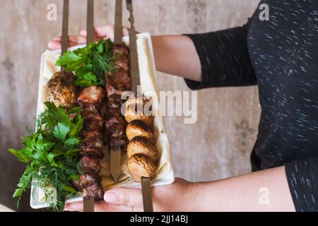 Il cameriere porta shish-kebab con verdure grigliate Foto Stock