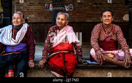 Vecchie donne nepalesi vestite con abiti tradizionali locali, seduti su una terrazza in pietra nella città di Bhaktapur, vicino Kathmandu città, in Nepal, Asia. Foto Stock