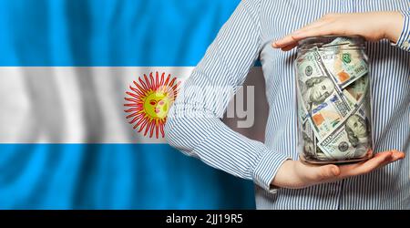 Mani con la banconota americana da 100 dollari e la bandiera del closeup Argentina Foto Stock
