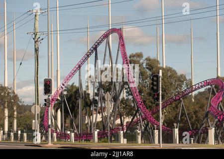 Vista dalla strada pubblica del Warner Brothers Movie World viola Hypercoaster emozionante corsa. Semaforo su Entertainment Drive, Oxenford, Queensland, Aus. Foto Stock