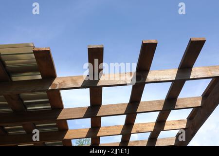 Montaggio su tetto in metallo su gazebo in legno marrone in una soleggiata giornata estiva vista dal basso verso l'esterno Foto Stock