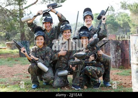 Gruppo di amici entusiasti giocatori di paintball in camouflage in piedi con le pistole Foto Stock