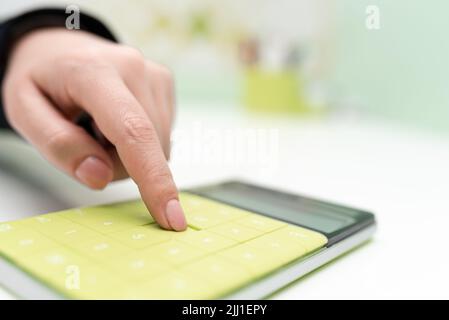 Donna d'affari che punta sulla calcolatrice sulla scrivania con notebook. Donna che preme sul fondo del tavolo con blocco note. Executive Visualizza informazioni recenti. Foto Stock