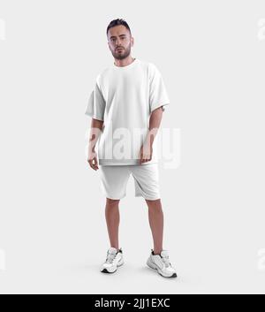 Mockup abito bianco moda, t-shirt oversize, shorts su un ragazzo bearded in sneakers, vista frontale, isolato sullo sfondo. Modello sportivo bianco, uomo Foto Stock