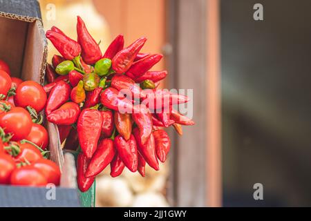 Mazzo di peperoncini rossi caldi appesi in un mercato di Street food, da vicino Foto Stock