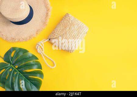 Tropical di foglie di palma, sun cappello di paglia con paglia borsa su sfondo giallo con copia spazio. Accessori da spiaggia vista superiore per vacanze estive concetto laici piatta Foto Stock