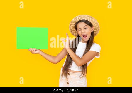 ragazza teen winking con spazio di copia su carta verde su sfondo giallo. ok Foto Stock