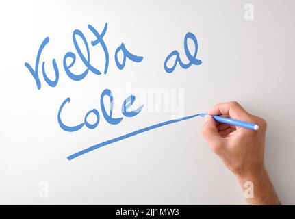 Scrittura manuale Vuelta al cole su tavola bianca con marcatore blu con fondo bianco isolato Foto Stock