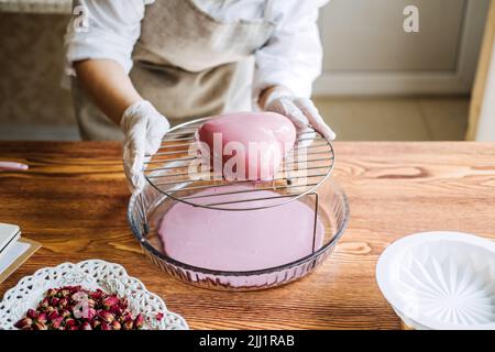 Torta di mousse. Torta di smalto a specchio. Processo di fabbricazione della torta di mousse a forma di cuore con smalto a specchio rosa Foto Stock