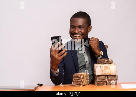 felice uomo d'affari africano con un sacco di soldi utilizzando un telefono Foto Stock