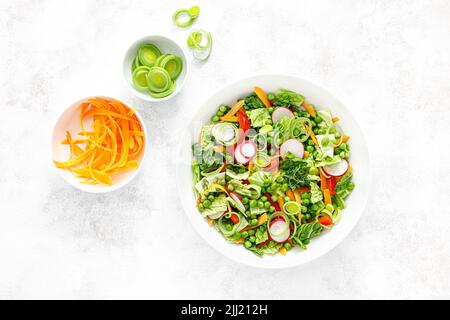 Insalata vegetariana fresca verde con cavolo di savoia, carota cruda, ravanello, peperone, porri e piselli verdi Foto Stock