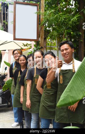 Il personale della caffetteria vietnamita sorride e si alza insieme contro un caffè Foto Stock