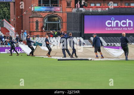 Le copertine stanno per scendere all'Emirates Old Trafford mentre il personale di terra prepara il campo dopo le soste della pioggia Foto Stock