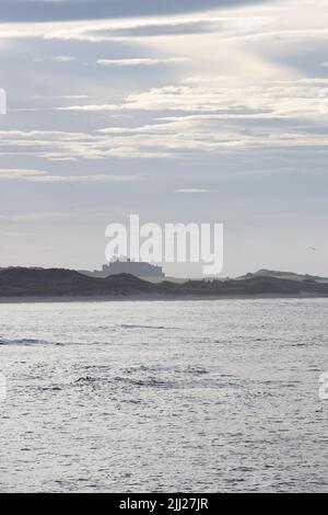 La silhouette del Castello di Bambburgh alla luce della sera dalle Seahouses, Northumberland, Inghilterra Foto Stock