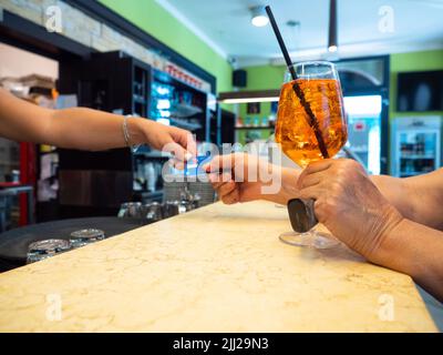 Primo piano bicchiere di Spritz aperol cocktail decorato con arancione su sfondo luminoso bar. Foto Stock