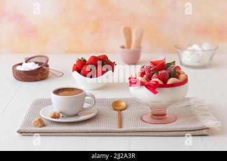 Charlotte, dessert francese con fragole, tazza di caffè e ingredienti su tavola di legno bianco. Messa a fuoco selettiva, vista ad angolo basso, nessuna persona. Foto Stock
