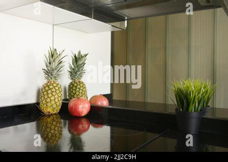 Ananas e melograni su ripiani e specchi Foto Stock