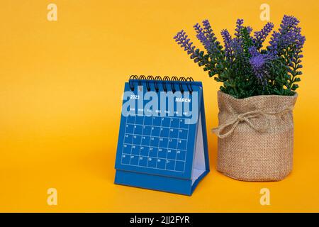 Marzo 2023 calendario da tavolo con pianta in vaso su sfondo giallo. Foto Stock