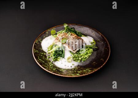 Pesce bianco cotto sulla pelle con asparagi verdi Foto Stock