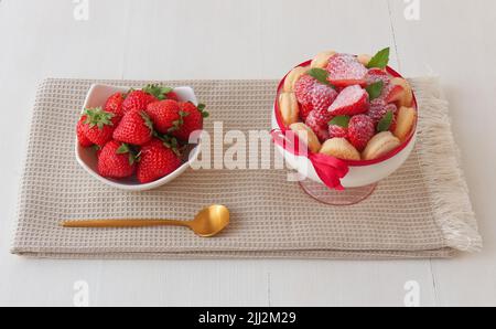 Charlotte, dessert francese con fragole legate con nastro di scarlatto, dessert facile e veloce fatto in un bicchiere. Vista ad angolo alto, senza persone. Foto Stock