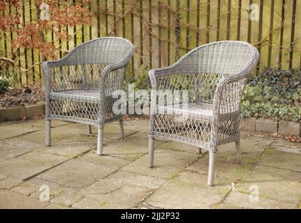 Due sedie da patio all'aperto in giardino o cortile. Mobili esterni fatti a mano in un'area salotto o in un cortile. Set di poltrone cottage con tradizionale Foto Stock