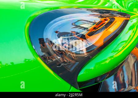 Poole, Dorset Regno Unito. 22nd luglio 2022. La folla si riversa su Poole Quay per ammirare le supercar McLarens per Poole Quay for My Car, un evento settimanale gratuito durante i mesi estivi con una linea di diverse marche di auto. Credit: Carolyn Jenkins/Alamy Live News - McLaren auto Reflection della McLaren supercar riflessa in faro di uno parcheggiato alle spalle. Foto Stock