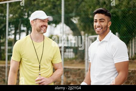 Youve ha ottenuto questo. Un bel giovane giocatore di tennis maschile in piedi fuori sul campo con il suo allenatore. Foto Stock