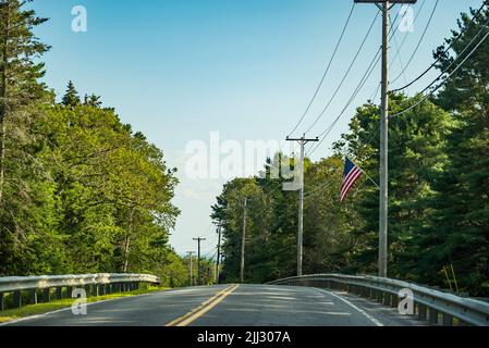 Strada principale di campagna che affievolisce nella distanza dell'orizzonte su un giorno di cielo blu, Maine Foto Stock