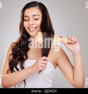 Posso fare curly o diritto e ancora guardare bene. Studio girato di una giovane donna spazzolando i capelli. Foto Stock