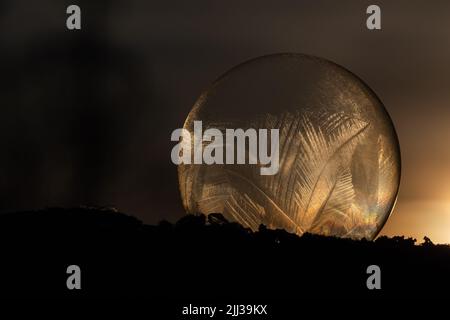 Bolle di sapone surgelate con motivo ghiaccio nella fredda giornata invernale al tramonto. Foto Stock