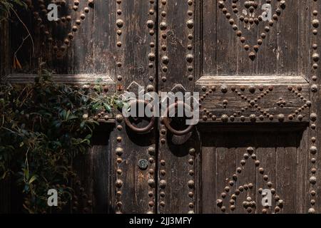 Sfondo con un'antica porta in legno con manopole tonde metalliche Foto Stock