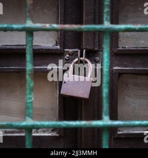 Vecchio lucchetto sulla vecchia porta di legno dietro una griglia Foto Stock