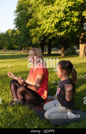 Madre di mezza età con bambino meditare insieme nel parco Foto Stock