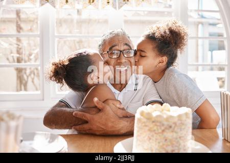 Il tempo vola come una freccia. Due grandi figlie baciano il loro nonno durante una festa di compleanno a casa. Foto Stock