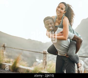 Una schiena forte rende un'amicizia forte, un giovane che dà alla sua ragazza un giro in pig-back. Foto Stock