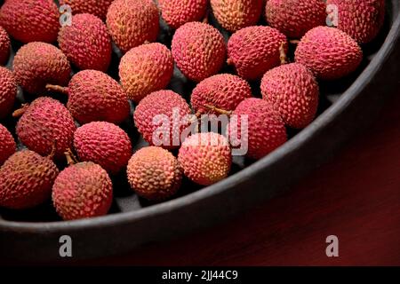 Frutta Lichia - sono piccoli frutti, con pelle rossastra e ruvidità. La polpa è bianca e succosa, dal sapore dolce e leggermente acido. Foto Stock