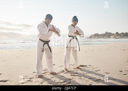 Un combattente deve avere onore. Scatto completo di due giovani artisti marziali che praticano il karate sulla spiaggia. Foto Stock