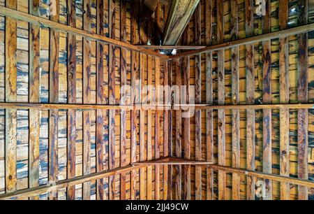 Una vista verso l'alto del soffitto a travi di legno di un fienile abbandonato Foto Stock