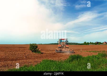 Il trattore aratri la terra. Preparazione per seminare e piantare. Immagine agricola Foto Stock