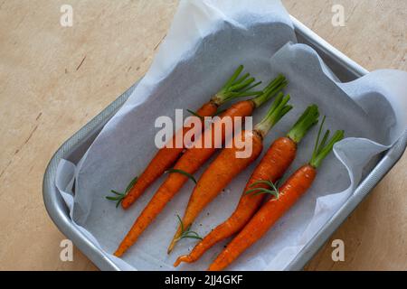 Carota intera giovane con verdure in teglia da forno Foto Stock