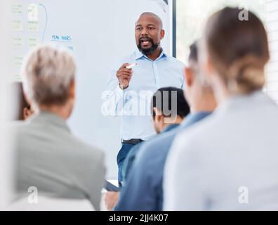 Il team di formazione e di insegnamento dei manager aziendali afroamericani maturi in ufficio. Uomo d'affari nero che usa una lavagna per parlare e spiegare Foto Stock
