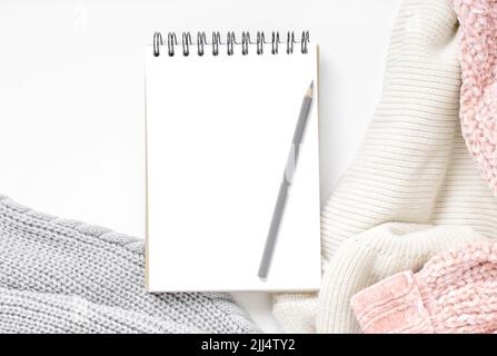 Home mock-up accogliente. Modello con un blocco note a spirale con schermo vuoto e maglia femminile moda maglione. Business, concetto di pianificazione Foto Stock
