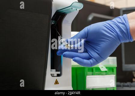 Operatore di laboratorio che utilizza un sistema di chimica clinica completamente automatizzato. Concetto di sistema di analisi automatizzato di laboratorio Foto Stock