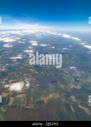 Concetto di viaggio aereo. Splendido scenario dall'aria attraverso la finestra dell'aereo. Guardando fuori dall'occhio del toro dell'aereo. Motore aereo e vista cielo blu. Foto Stock